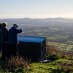 3 people stood on clee hill looking at the view