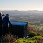 3 people stood on clee hill looking at the view