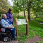 2 ladies, 1 in a wheelchair, looking at a sign in Darnford Valley
