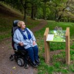1 ladies in a wheelchair looking at a sign in Darnford Valley