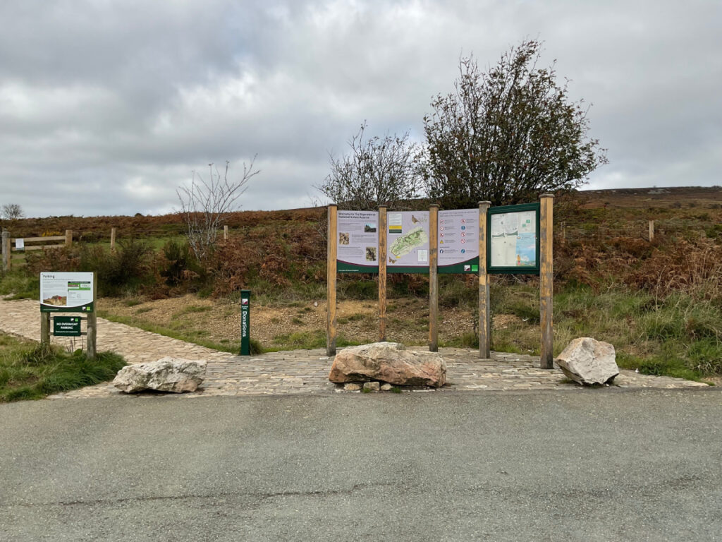Photo of various information signage at The Knolls. There are also low level rocks in front of the panels that may provide as a barrier.