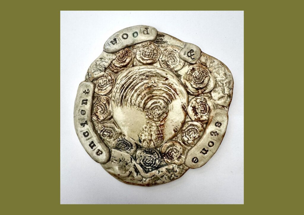 A circular organic shaped ceramic tile is decorated with a green and brown glaze and relief textured patterns depicting the landscape.