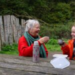Two people enjoying a hot drink on a picnic bench
