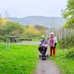 Two people near a picnic bench in Poles Coppice. Earl's hill is visible in the background.