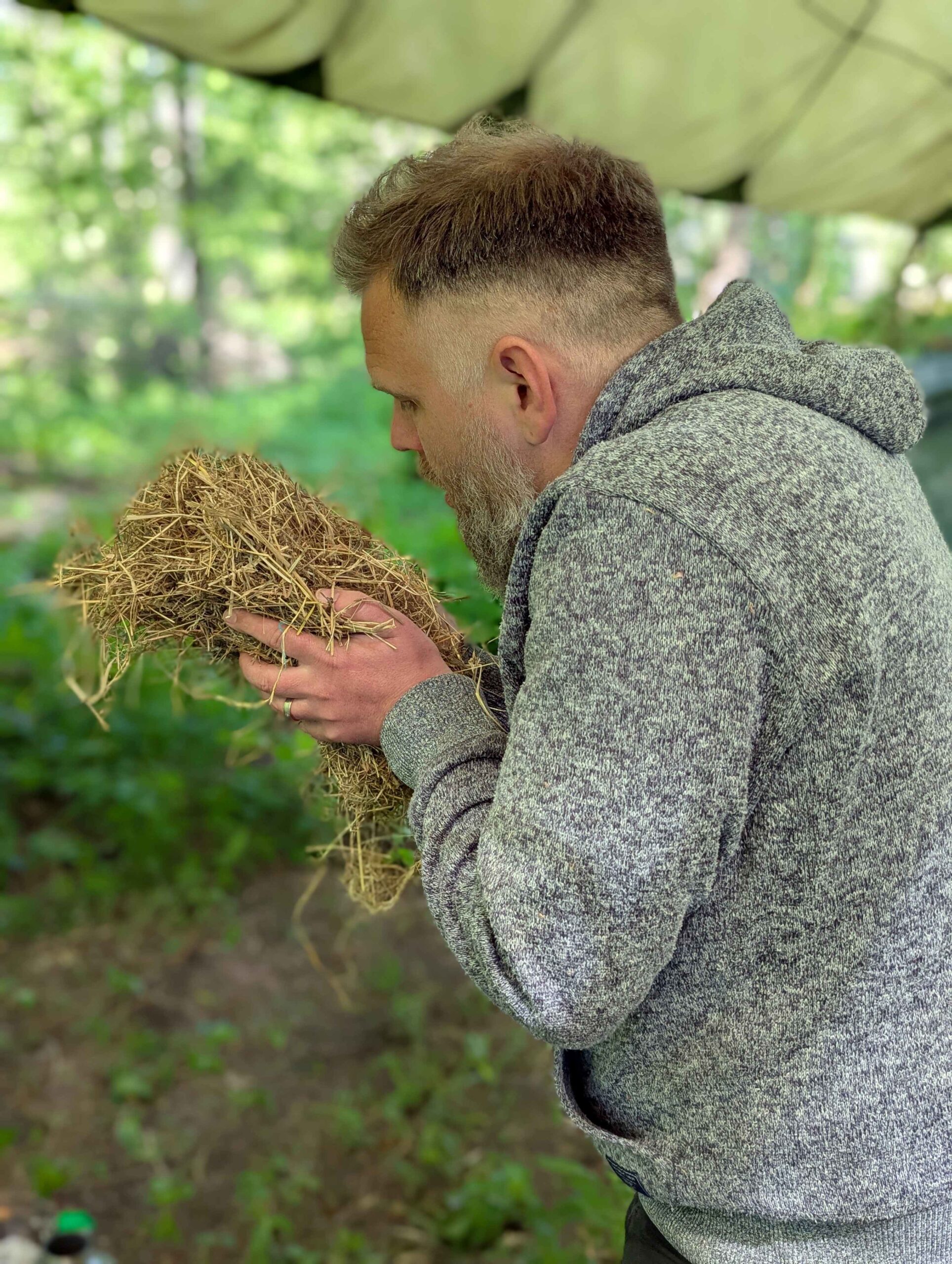 man blowing on straw to start a fire