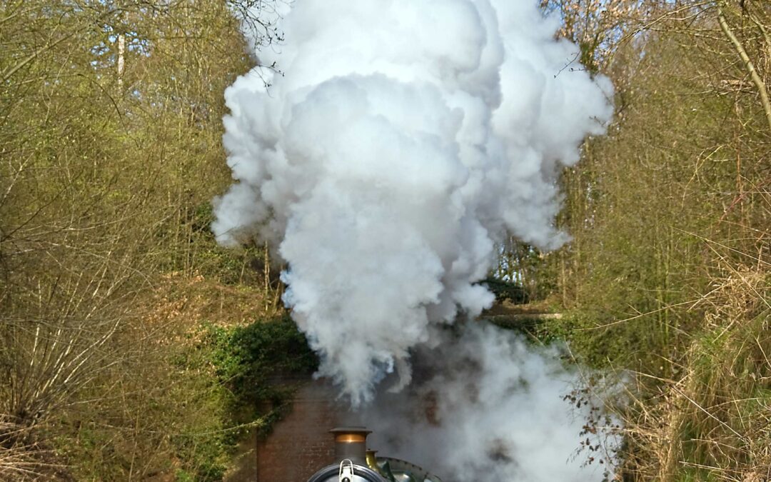 steam train on track with steam coming out of it.